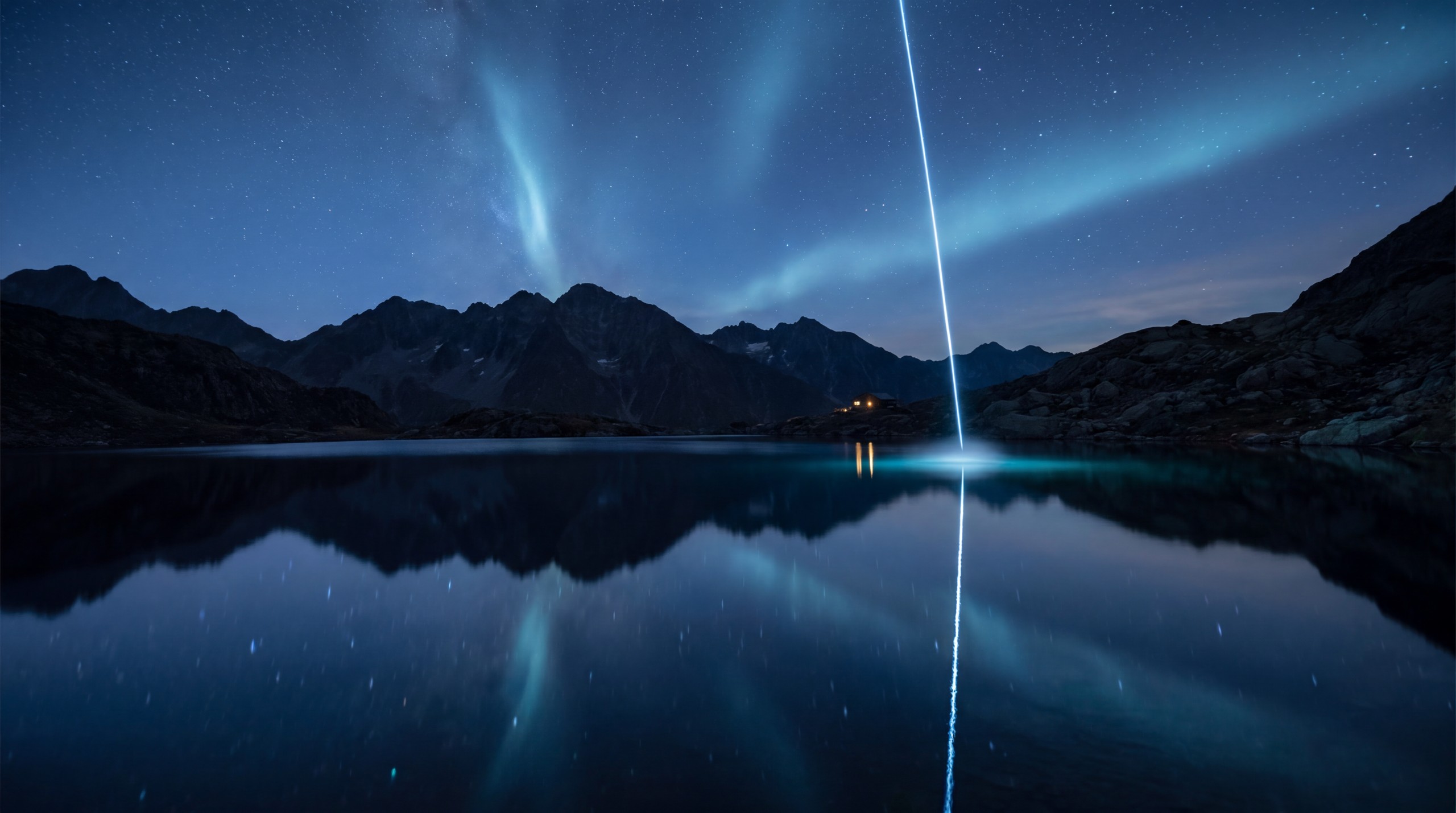 Bergsee bei Nacht mit eisblauer Lichtlinie